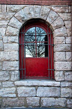 Red barred window in stone wall