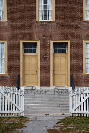 Open gate and steps leading to two yellow doors.
