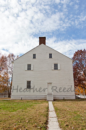 Narrow sidewalk leading to a Shaker style historical home.