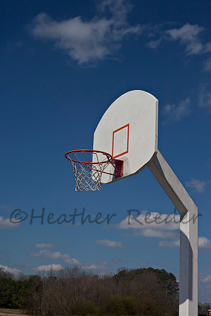Recreation basketball goal and cloudy blue sky.