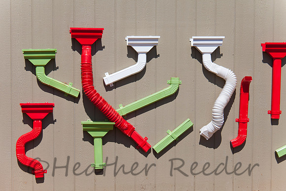 Various shapes and designs of colorful gutters displayed on wood wall.