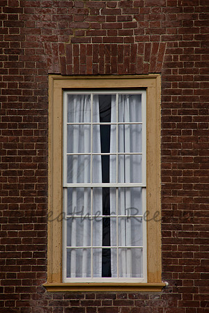 Single yellow framed window on red brick wall.