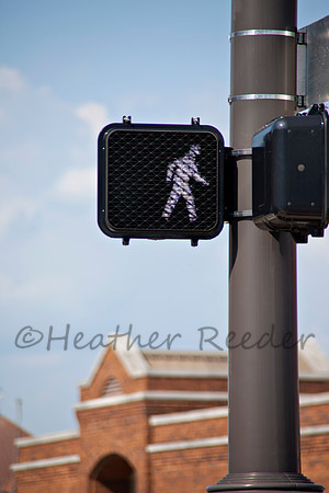 Electronic crosswalk sign surrounded by blue sky and brick build