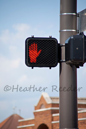 Electronic crosswalk sign with warning hand signal.