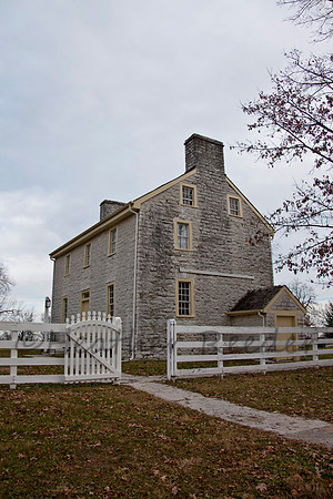 Paved pathway and open gate leads to old style Shaker home.