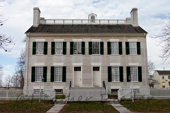 Shaker historical home behind a white picket fence.