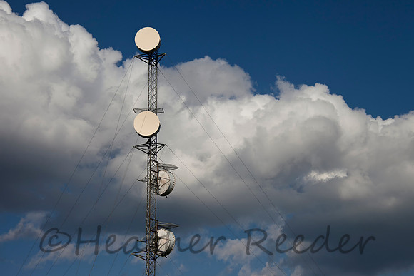 Communication tower surrounded by white clouds and blue sky