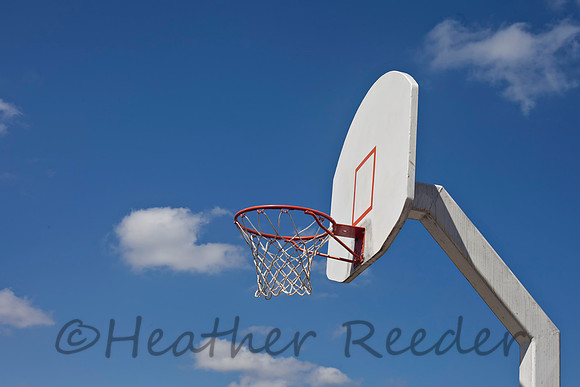 Retro recreational basketball goal surrounded by cloudy blue sky.