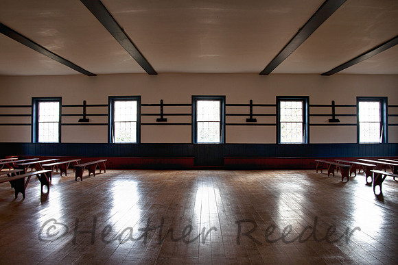 Old, open meeting room with antique wood floors and simple wood benches.