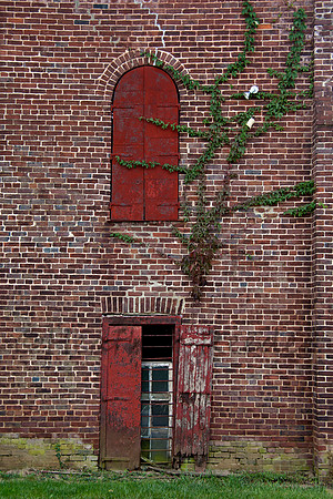 Two different shaped windows on vintage brick wall with many different textures.